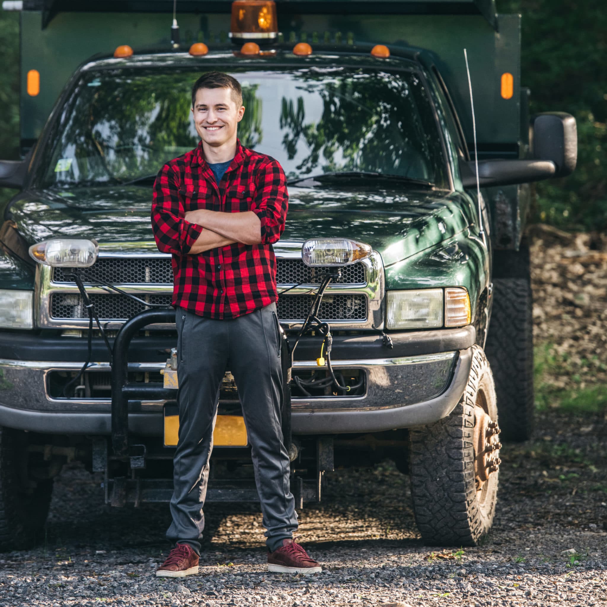 Happy smiling young man standing in front of pickup truck
